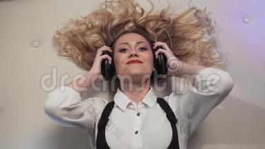 女人躺在床上，慢慢地把耳机放在耳朵上，对音乐做出反应，随着音乐轻柔地旋转。